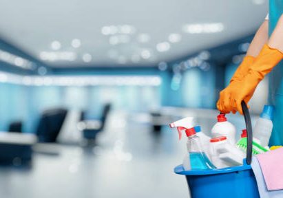 istockphoto-1442185202-612x612 Concept cleaning service business premises. Cleaning lady holding a bucket of cleaning products against the backdrop of an office in a business center.